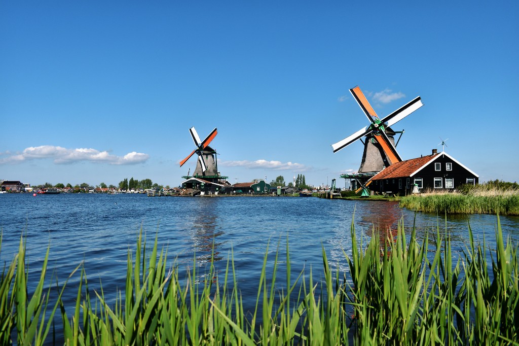 Traditional Dutch windmills along a waterway under a clear blue sky